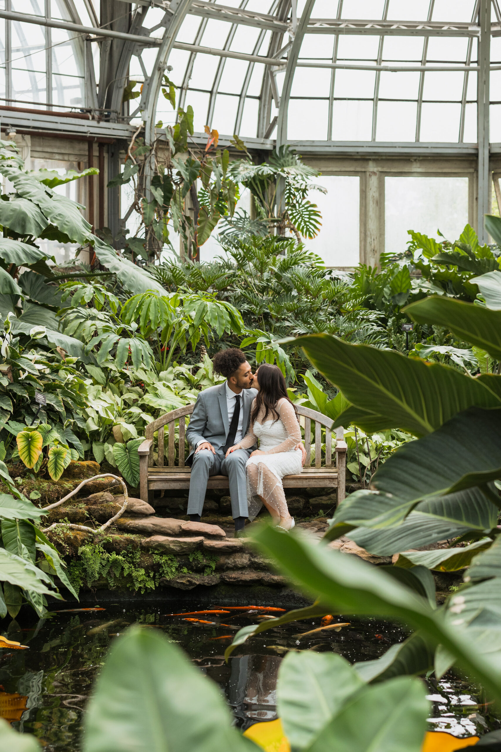 bride and groom kissing in greenhouse