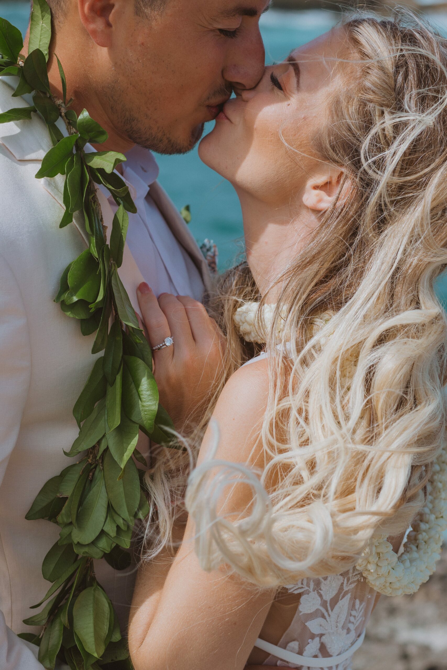 bride and groom wearing leis and kissing