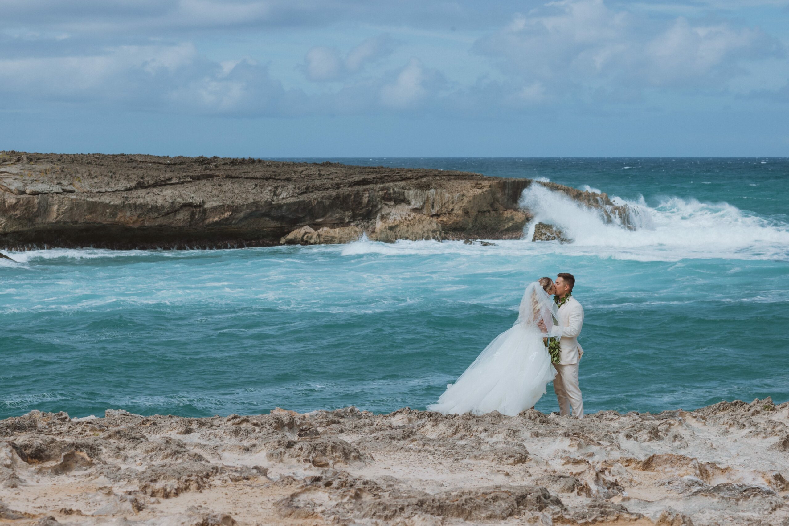 bride and groom kissing by waves